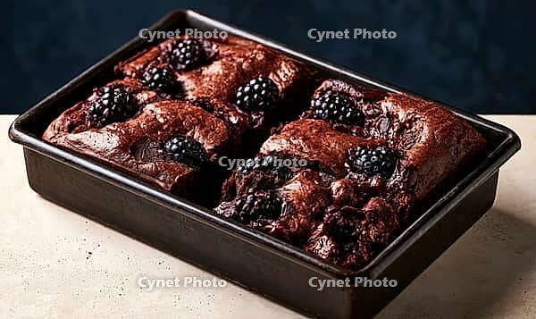 Freshly baked chocolate brownies topped with blackberries in a baking pan, AI generated [IBR125448909]