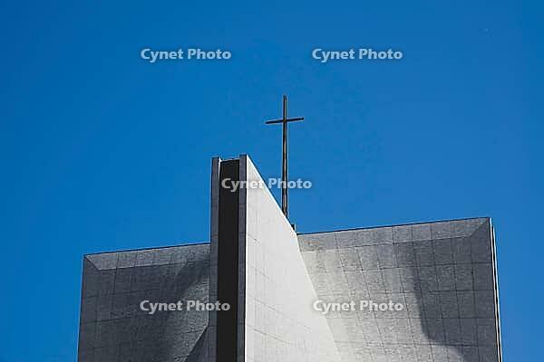 Architecture detail with cross on a modern church building against blue sky [IBR125462088]