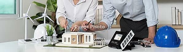 Two people working on a project, one wearing a blue helmet. The project is a house design and people use a whiteboard to sketch their ideas [IBR125462100]