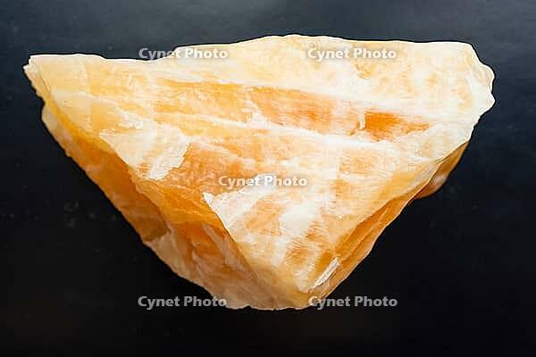 Specimen of mineral from geological collection - natural orange calcite rock close-up on black background [IBR125462113]