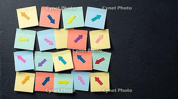 Blank colorful sticky notes with small arrow markers pointing in different directions on charcoal slate wall, indecision concept, studio shot, AI generated [IBR125472310]