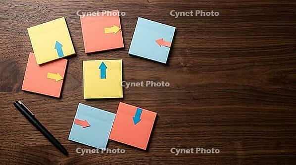 Top view of blank sticky notes with arrow markers pointing in different directions scattered on dark walnut desk beside black pen, studio shot, AI generated [IBR125472316]