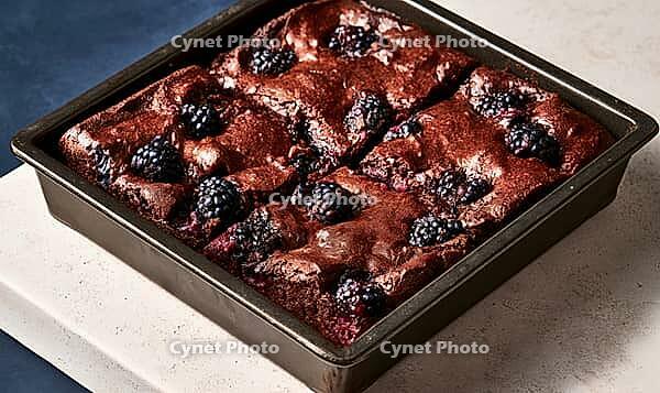Freshly baked chocolate brownies topped with blackberries in a baking tray, AI generated [IBR125472323]
