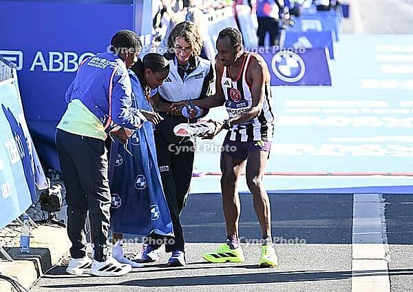 27 September 2026, Athletics: BMW Berlin Marathon 2026, from left: Tigst Assefa (ETH 2:11:04) crosses the finish line, exhausted, and is supported by a team at the 2026 BMW BERLIN MARATHON [IBR113453172]