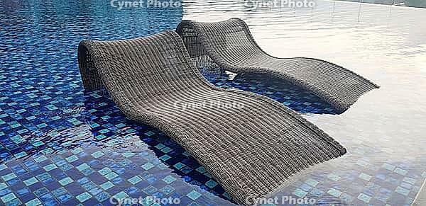 Relax deck chair at blue pool by swimming pool in luxury spa resort or villa crisis of tourism industry after Kovid-19 coronavirus pandemic travel lifestyle in family summer vacation [IBR125492335]