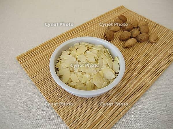 Planed almonds, almond leaves as a snack in a small porcelain bowl [IBR125492350]