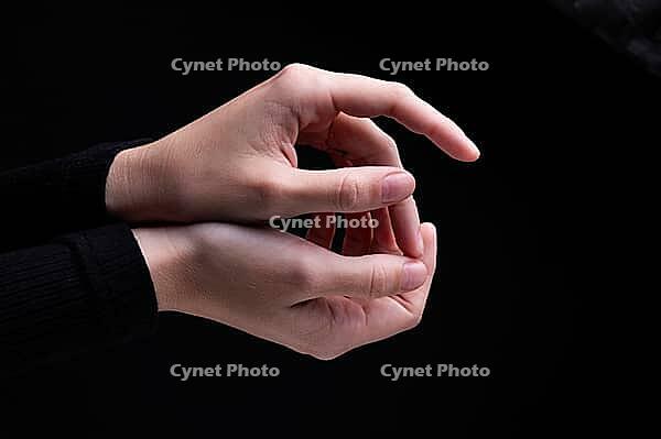 Close-up image of beautiful female hands with delicate pink manicure on nails on black background. Hand skin care, manicure and beauty treatments. Elegant and graceful hands with thin graceful fingers [IBR125492405]