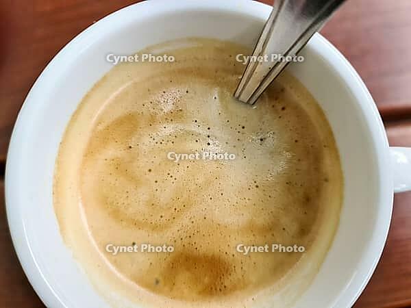 Close up view at a coffee surface in white a cup on a brown wooden background [IBR125501553]