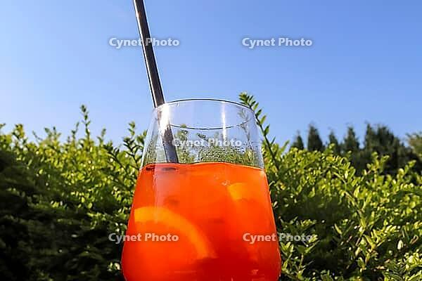 Refreshing orange summer cocktails with ice against a blue sky background [IBR125501594]
