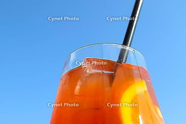Refreshing orange summer cocktails with ice against a blue sky background [IBR125501596]