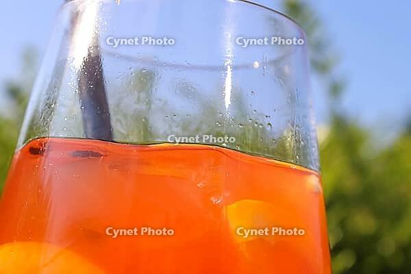 Refreshing orange summer cocktails with ice against a blue sky background [IBR125501620]
