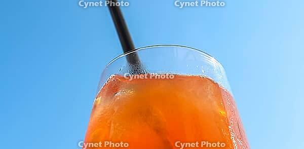 Refreshing orange summer cocktails with ice against a blue sky background [IBR125501622]