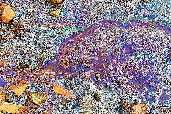 Colorful fuel and oil on an asphalt texture showing heavy enviromental pollution [IBR125501630]