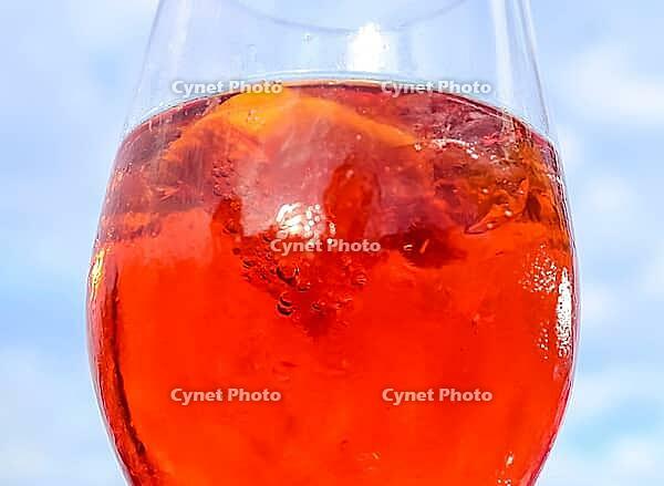 Refreshing orange summer cocktails with cola and ice against a blue sky background. Close up view [IBR125501635]