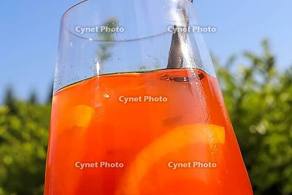 Refreshing orange summer cocktails with ice against a blue sky background [IBR125501636]