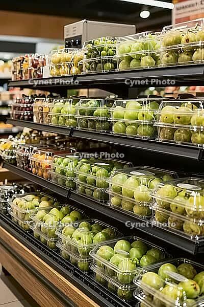 Fresh green fruits in transparent plastic clamshell boxes line dark supermarket shelves, showing modern food preservation and retail distribution, synthetic polymers encase organic agricultural goods in orderly multi level displays, highlighting the tensi [IBR125502126]