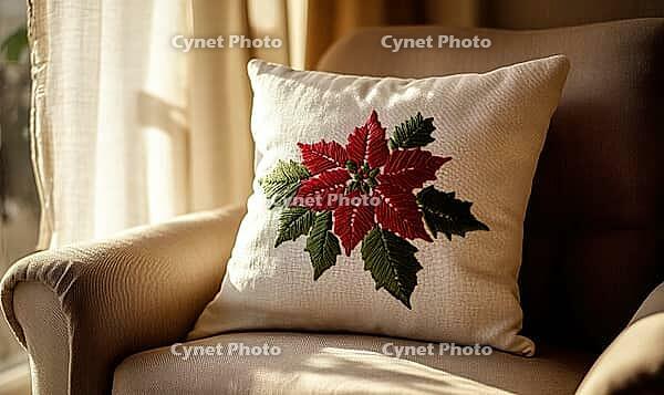 White pillow with red and green poinsettia embroidery, placed on a beige linen armchair, AI generated [IBR125502130]