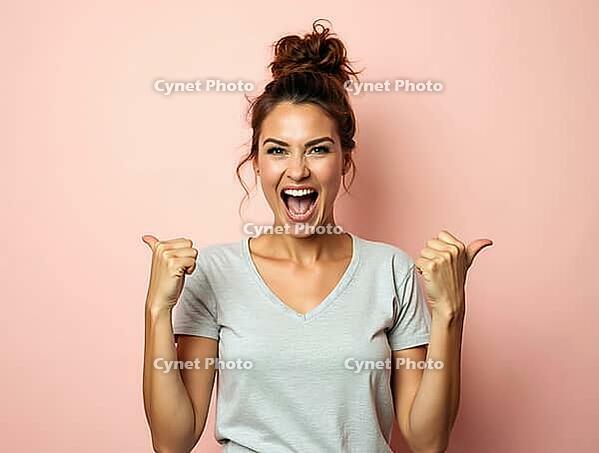 Excited young woman pointing sideways with both thumbs and cheerfully yelling, expressing excitement and enthusiasm on a pastel pink background, AI generated [IBR125502148]