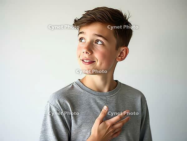 Thoughtful teenage boy gesturing with his hand on his chest while looking upwards with a smile, AI generated [IBR125502150]