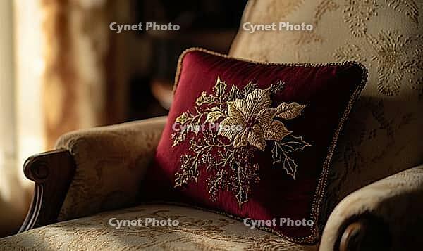 Deep red pillow with gold poinsettia embroidery, paired with dark green accents, set on a beige armchair, AI generated [IBR125502152]