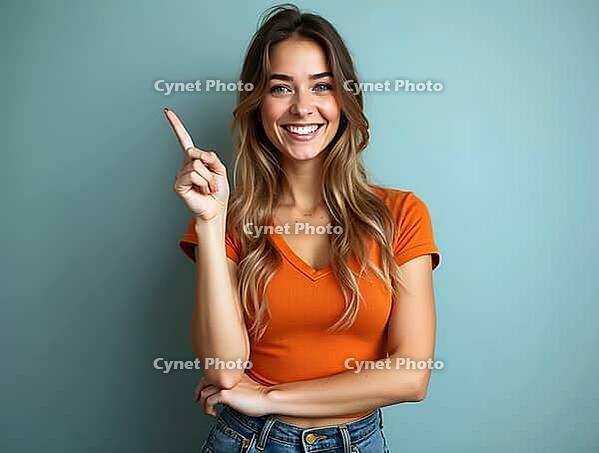 Studio portrait of a cheerful young woman pointing her finger up while smiling on a blue background, AI generated [IBR125502157]