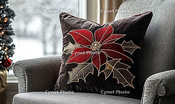 Dark chocolate pillow with bright red poinsettia and gold stitching, on a warm gray armchair, AI generated [IBR125502162]