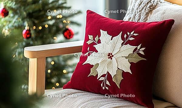 Dark red pillow with delicate white poinsettia embroidery on a light wooden bench, AI generated [IBR125502170]