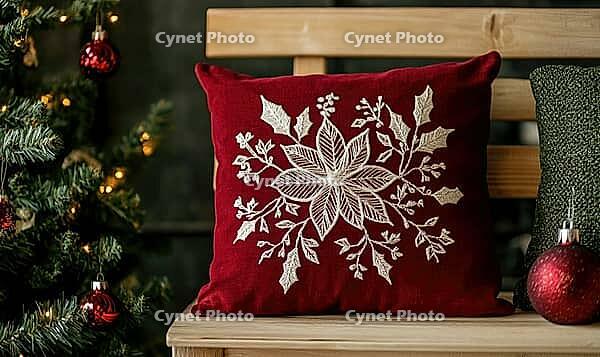 Dark red pillow with delicate white poinsettia embroidery on a light wooden bench, AI generated [IBR125502172]