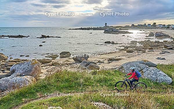 Nice senior woman cycling with her electric mountain bike at the rocky rose granite coast at Meneham site in Kerouarn, Brittany, FranceKerouarn [IBR125521079]