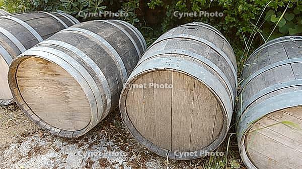 Several large wine barrels lie on a gravelly ground in the countryside, Patras, Greece [IBR125521083]