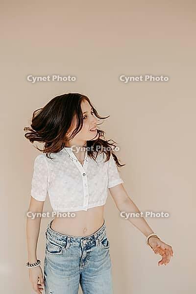 Long-haired brunette girl, 11, in portrait against beige background [IBR125521090]