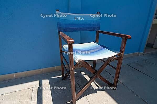 Wooden folding chair standing on blue house wall, Punta Marina, Ravenna, Emilia-Romagna, Italy [IBR125521096]