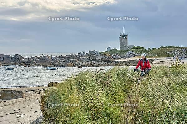 Nice senior woman cycling with her electric mountain bike at the rocky rose granite coast at Meneham site in Kerouarn, Brittany, FranceKerouarn [IBR125521106]