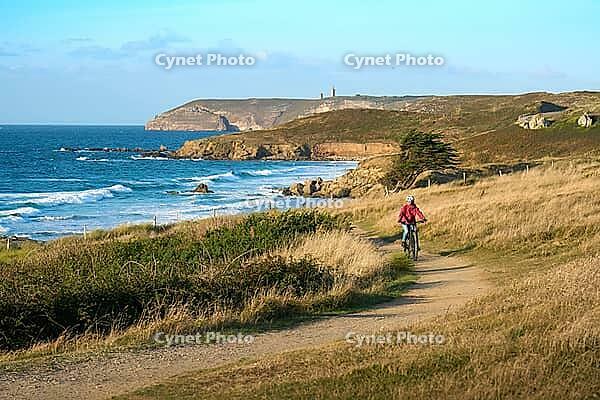 Active senior woman cycling with her electric mountain bike along the wild atlantic coast of Finisterre at Cape Frehel, Brittany, France [IBR125521114]