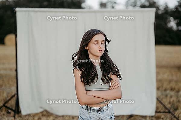 Brown-haired girl, 11, in a cornfield against a beige background [IBR125521131]