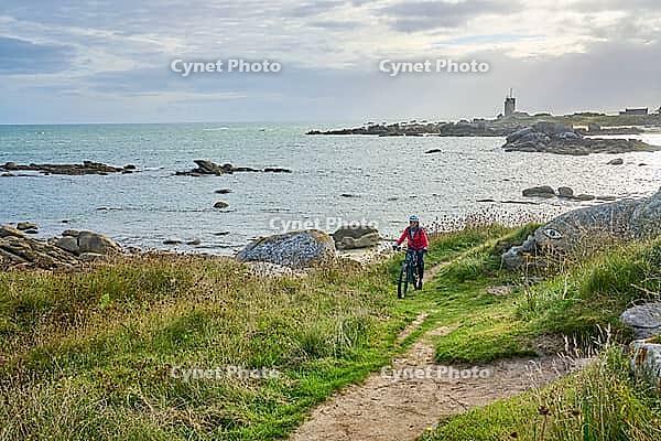 Nice senior woman cycling with her electric mountain bike at the rocky rose granite coast at Meneham site in Kerouarn, Brittany, FranceKerouarn [IBR125521136]