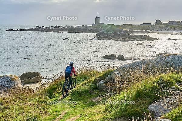 Nice senior woman cycling with her electric mountain bike at the rocky rose granite coast at Meneham site in Kerouarn, Brittany, FranceKerouarn [IBR125521153]