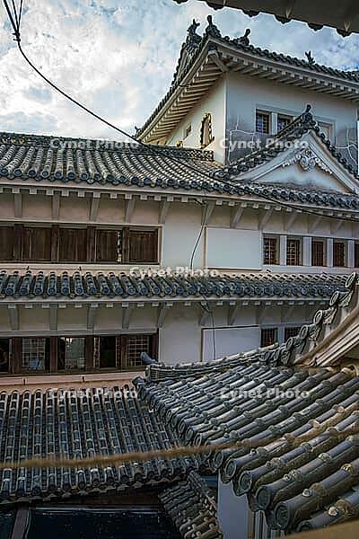 Himeji, Japan - Sep 24 2024, vertical, panoramic view from window of roofs and towers with roof tiles in courtyard of Himeji Castle, White Heron Castle, at daytime with cloudy sky, Himeji, Japan [IBR125527039]