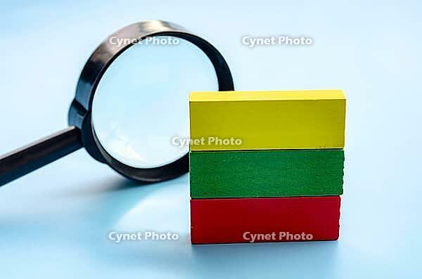 Colorful stacked wooden blocks with a magnifying glass on a wooden surface, representing learning and discovery [IBR125527042]