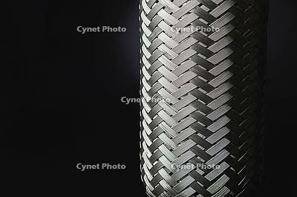 Exhaust Flexible Joint For Car System. Automotive Stainless Steel Muffler Connection. The new metal part is welded to the pipe. repair. Close-up. Black and white [IBR125527055]