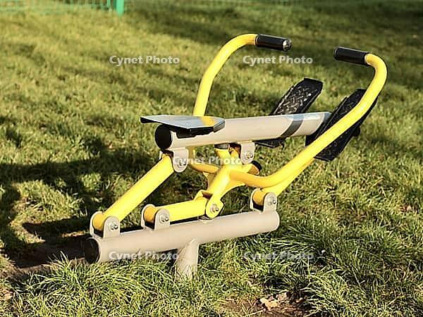 Street rowing yellow exercise machine on green grass in the yard in the city. [IBR125527068]