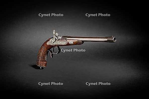 Studio shot of historic percussion disc gun pistol short weapon on black background with drop shadow dramatic light [IBR125527071]