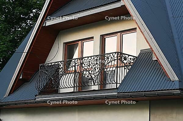 House exterior with attic and balcony creates cozy residential architecture scene. Home features decorative railings, modern design elements and suburban atmosphere for real estate, lifestyle [IBR125527081]