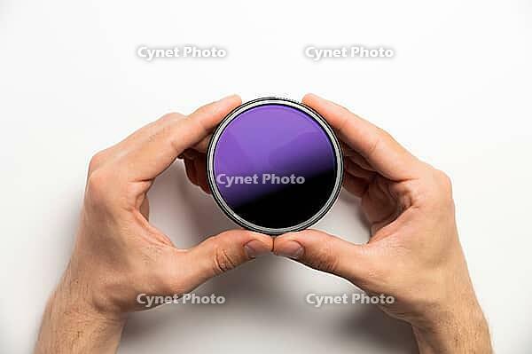 Polarizing filter for camera in male hands on a white background, close-up [IBR125527101]