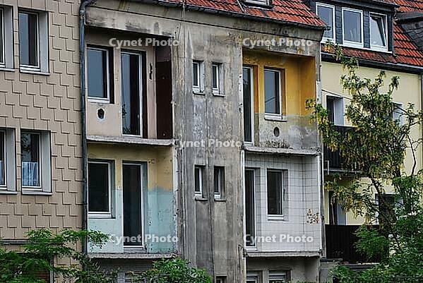 Old house with demolished balconies and weathered walls in Essen, Germany [IBR125527102]