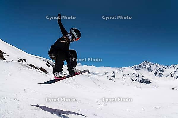 Young woman snowboarder jumping from a springboard in the snowy mountains [IBR125536392]
