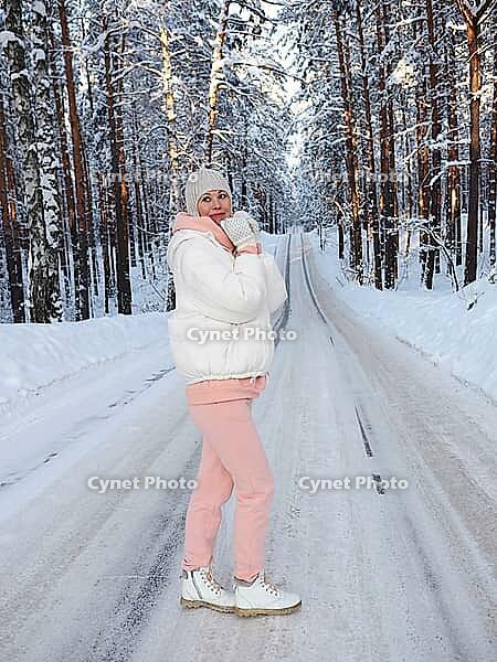 A young girl on the road in a winter forest. Beautiful winter forest with a road. Travel in winter. [IBR125536400]