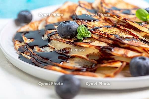 Sweet pancakes served with chocolate sauce, mint and blueberries, close-up. Selective focus [IBR125536435]