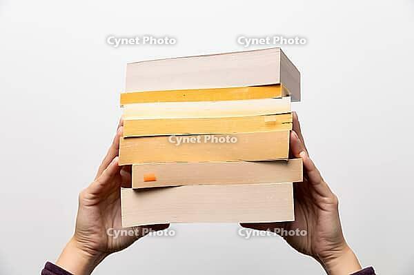 Stack of books in hand, Book Day, several books in hands on neutral white background. Home leisure. Self-isolation home, home schooling [IBR125536450]