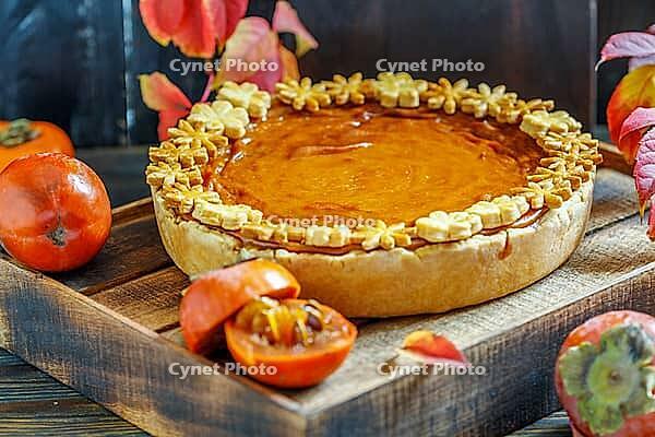 Homemade pumpkin pie, juicy persimmons and colorful autumn leaves on dark wooden background [IBR125557532]